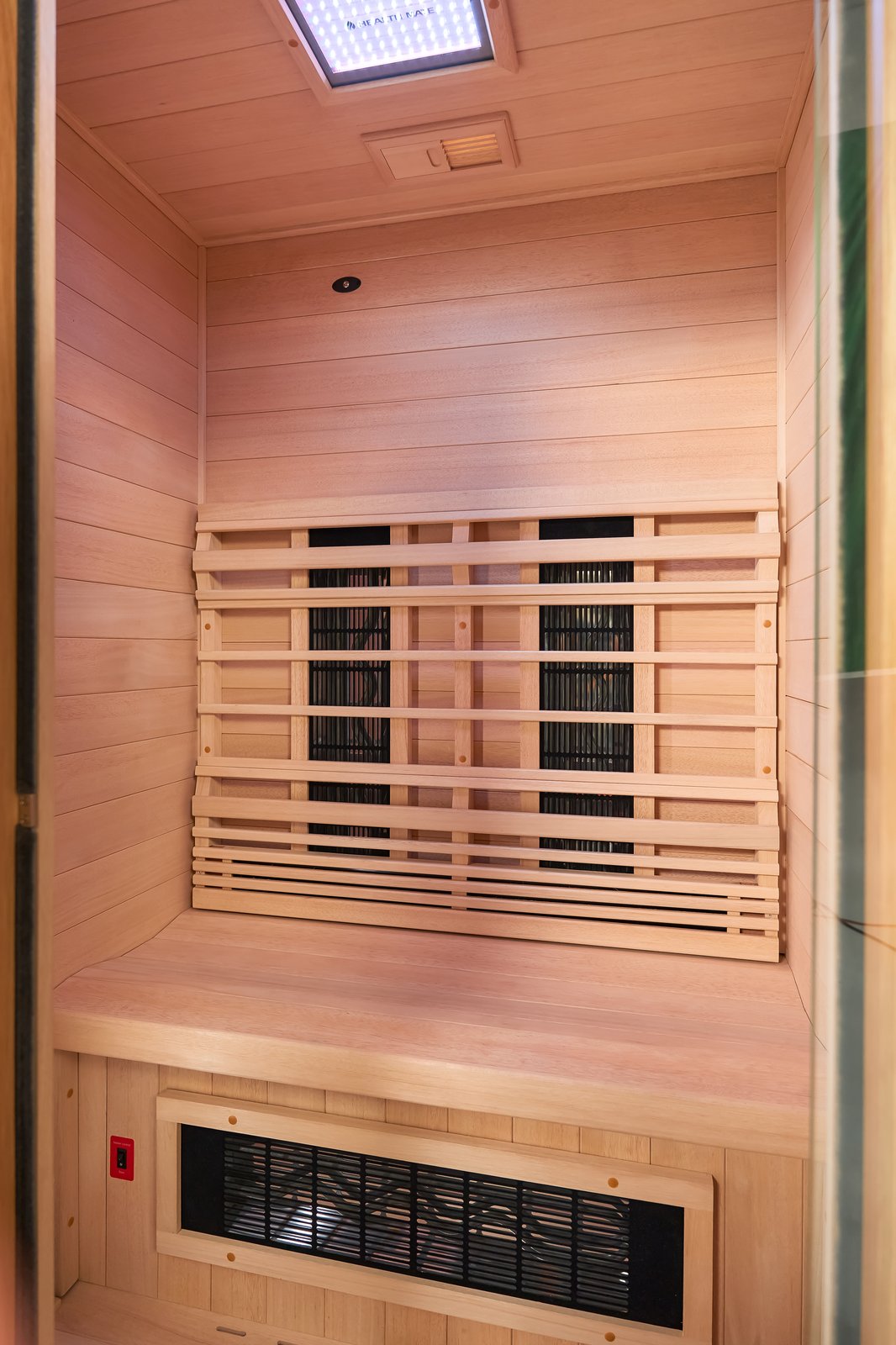 Inside the Health Mate cedar cabin &mdash; warm wood, infrared heaters, and soft chromotherapy lighting
