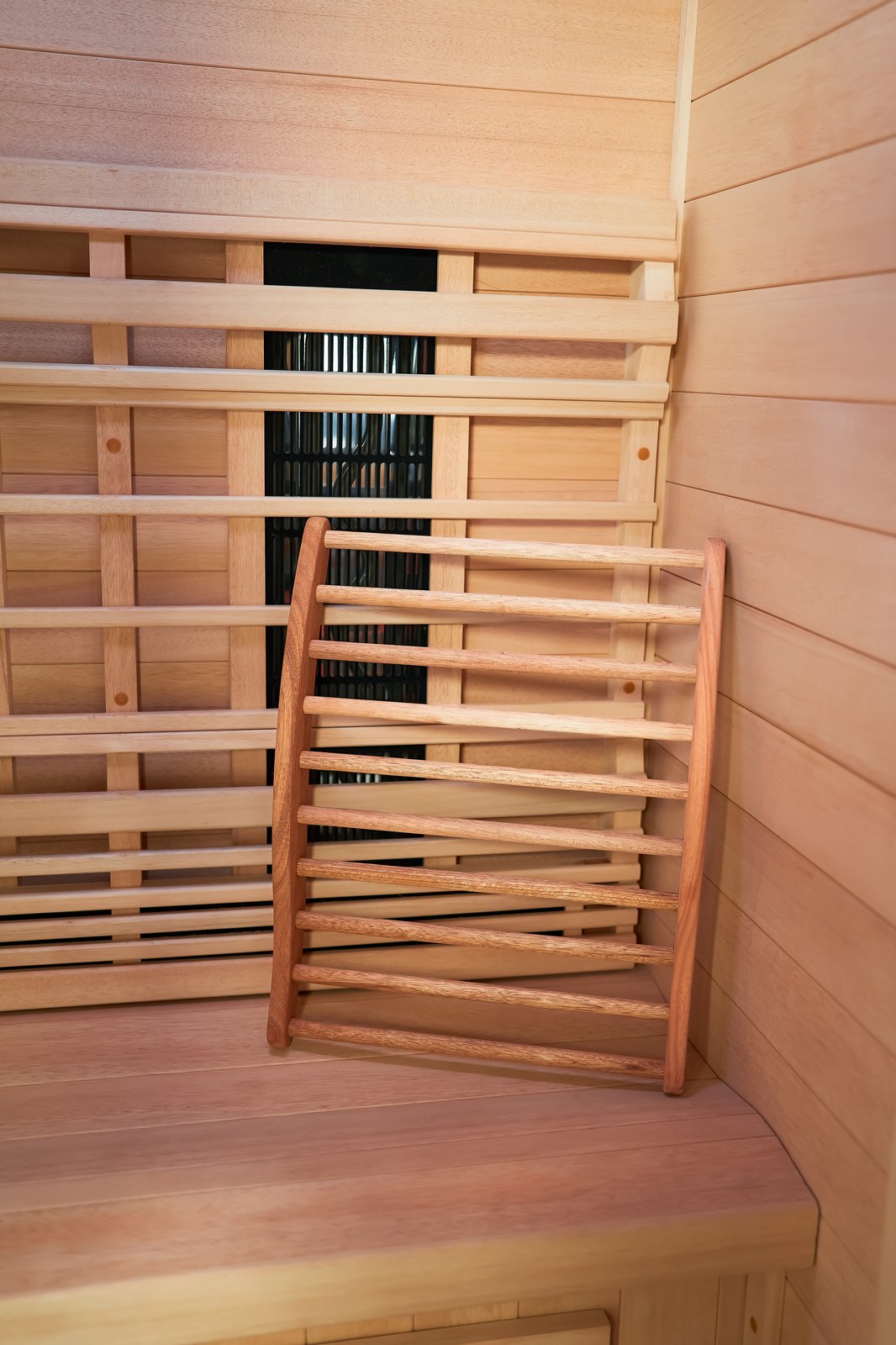 Ergonomic curved cedar backrest inside the sauna